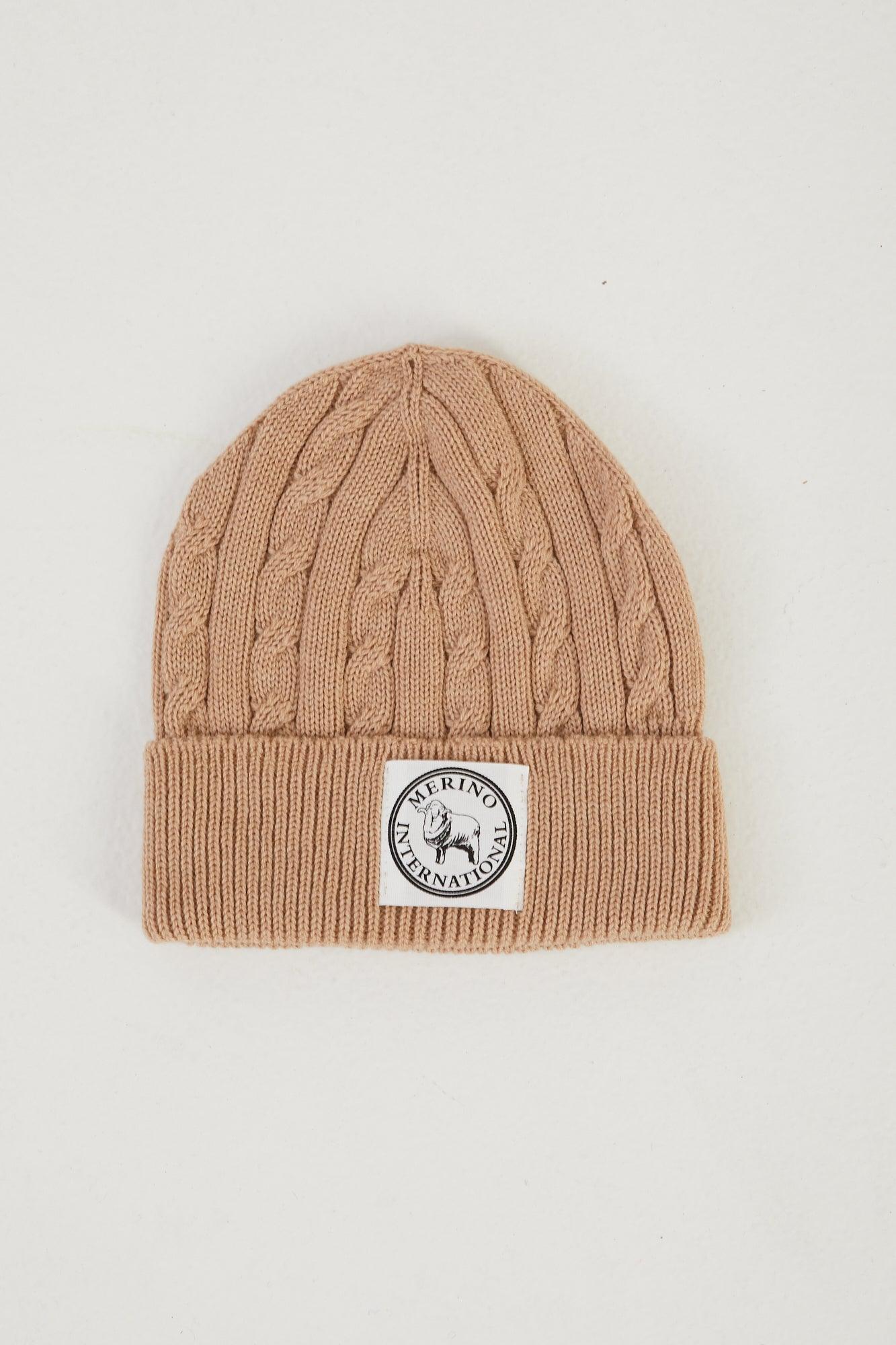 Flat lay of a merino wool cable knit beanie in camel