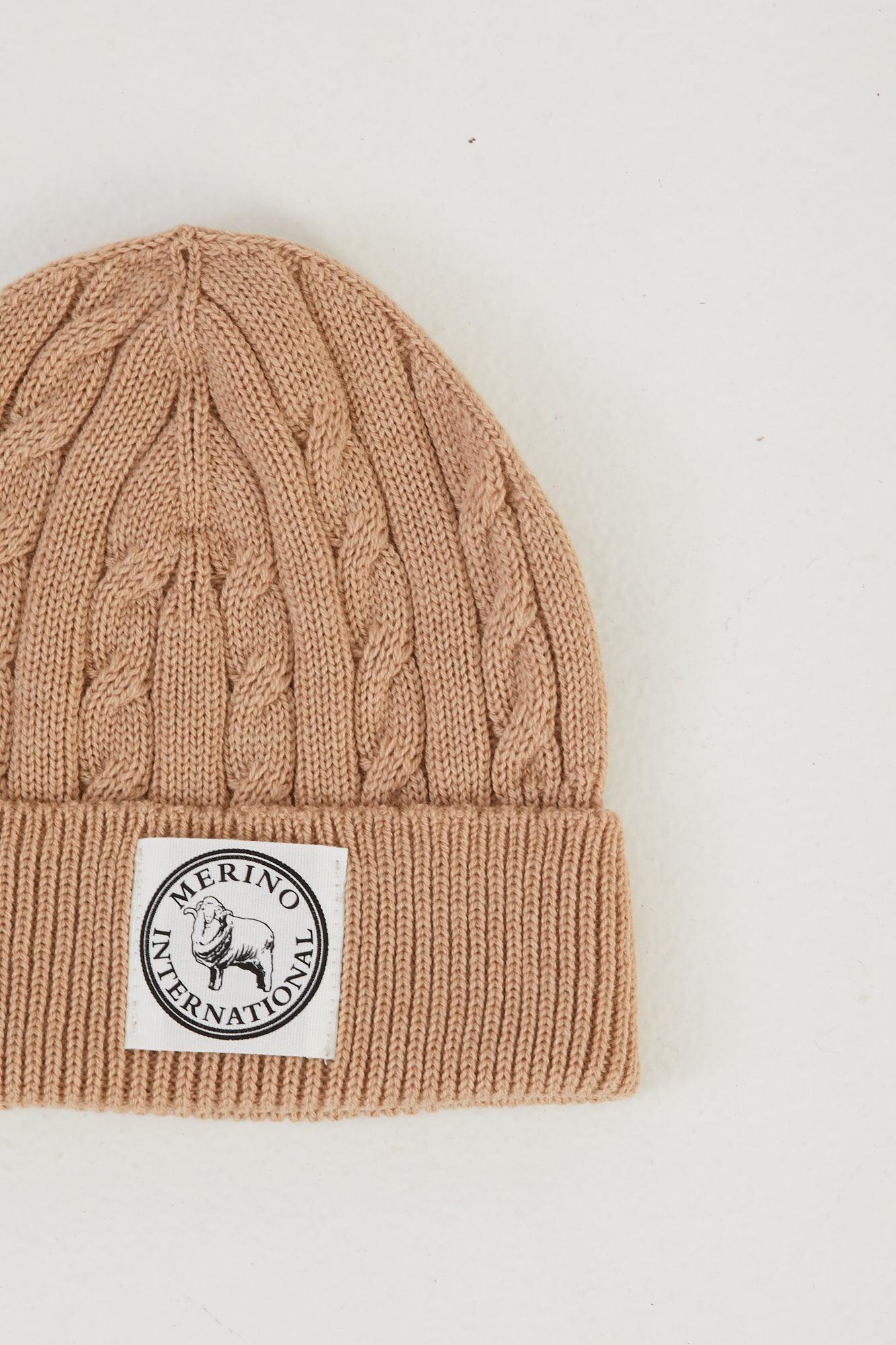 Zoomed in image of a merino wool cable knit beanie in camel flat lay